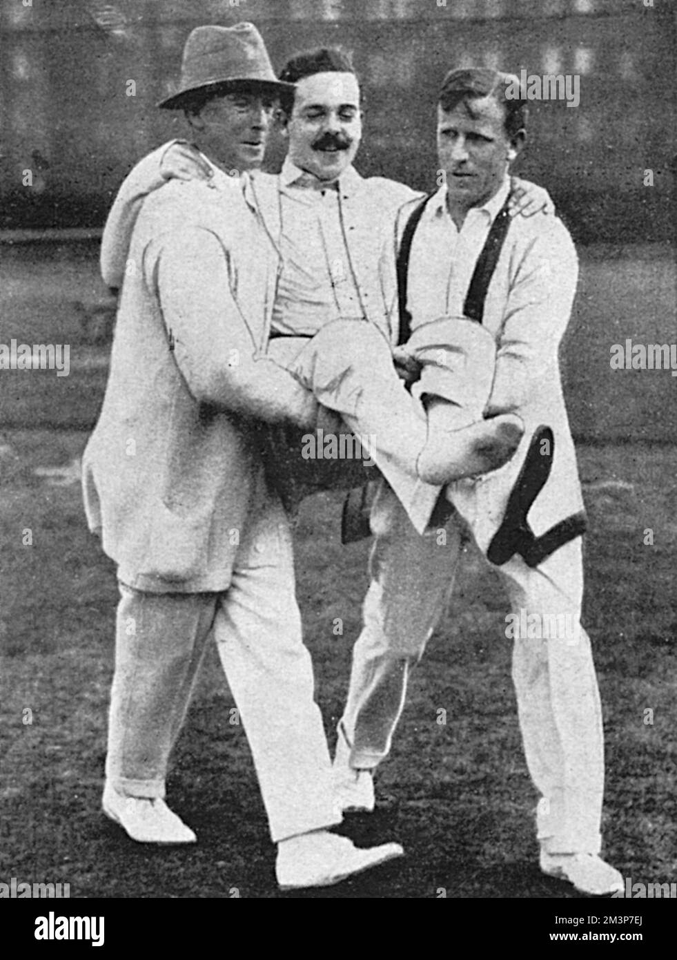 The exiled King Manuel of Portugal, a great tennis fan, pictured being carried off court by M. J. G. Ritchie and S. N. Doust after straining the tendon on his left leg during a match in which he partnered Mrs Lambert Chambers at Queen's Club.       Date: 1916 Stock Photo