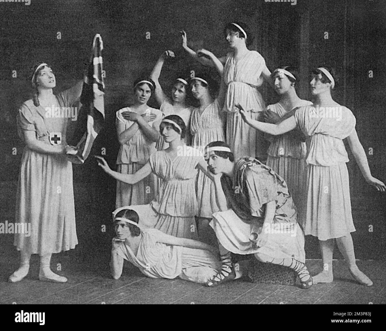 Madame Karina, Danish prima ballerina, pictured with a number of her pupils, all children or sisters of serving officers, taking part in a dance called The Good Angel.  She is seen far left wearing the red cross and carrying a Union Jack flag.  As a fellow Dane, Queen Alexandra was patron of the dancing school.  1915 Stock Photo