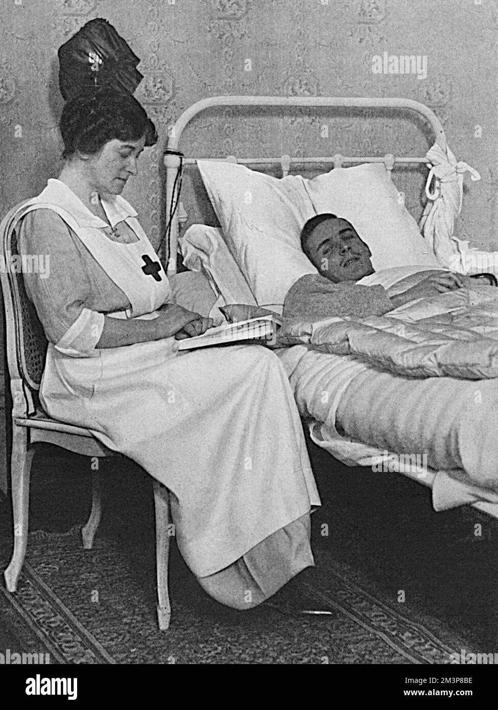 Almina Herbert, Countess of Carnarvon (15 August 1876  8 May 1969), English aristocrat, wife of George Herbert, 5th Earl of Carnarvon, and ch&#x2d25;laine of Highclere Castle, Newbury.  Pictured reading to a wounded officer at Highclere, where a large portion of the house had been turned into hospital for the wounded.  Lady Carnarvon was the daughter of Mr Frederick Charles Wombwell (though her natural father was the millionaire banker, Leopold de Rothschild)  and married the earl in 1895.       Date: 1914 Stock Photo