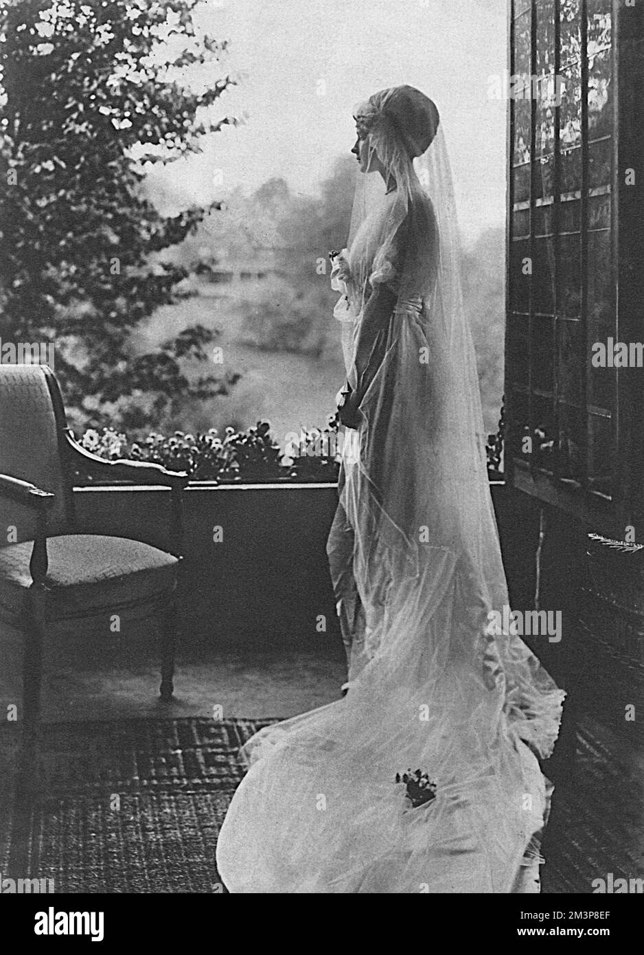 Artistic photograph showing a bride in veil and dress, looking pensively out of a window, perhaps in the knowledge that her new husband will soon be leaving for the front.  A subsequent photograph on the following page (image number 10700922) depicted a war widow.       Date: 1915 Stock Photo