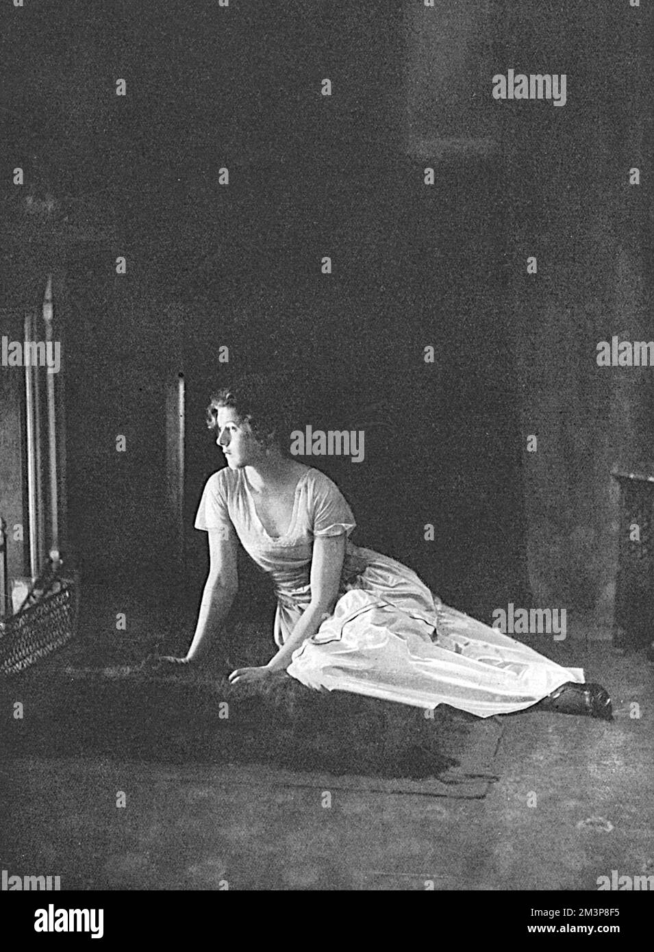 Clarissa Madeleine Georgiana Felicite Tennant (1896 - 1960), daughter of 1st Baron Glenconner pictured staring into the fire.  She was one of the last debutantes to be presented at court in the summer of 1914, before the Great War interrupted the tradition.  She married three times, first to Adrian Bethell in 1915 (divorced 1918), then to Major Lionel Tennyson and finally to James Beck.  Barbara Cartland described her as, 'the most beautiful woman I had ever seen.' Stock Photo