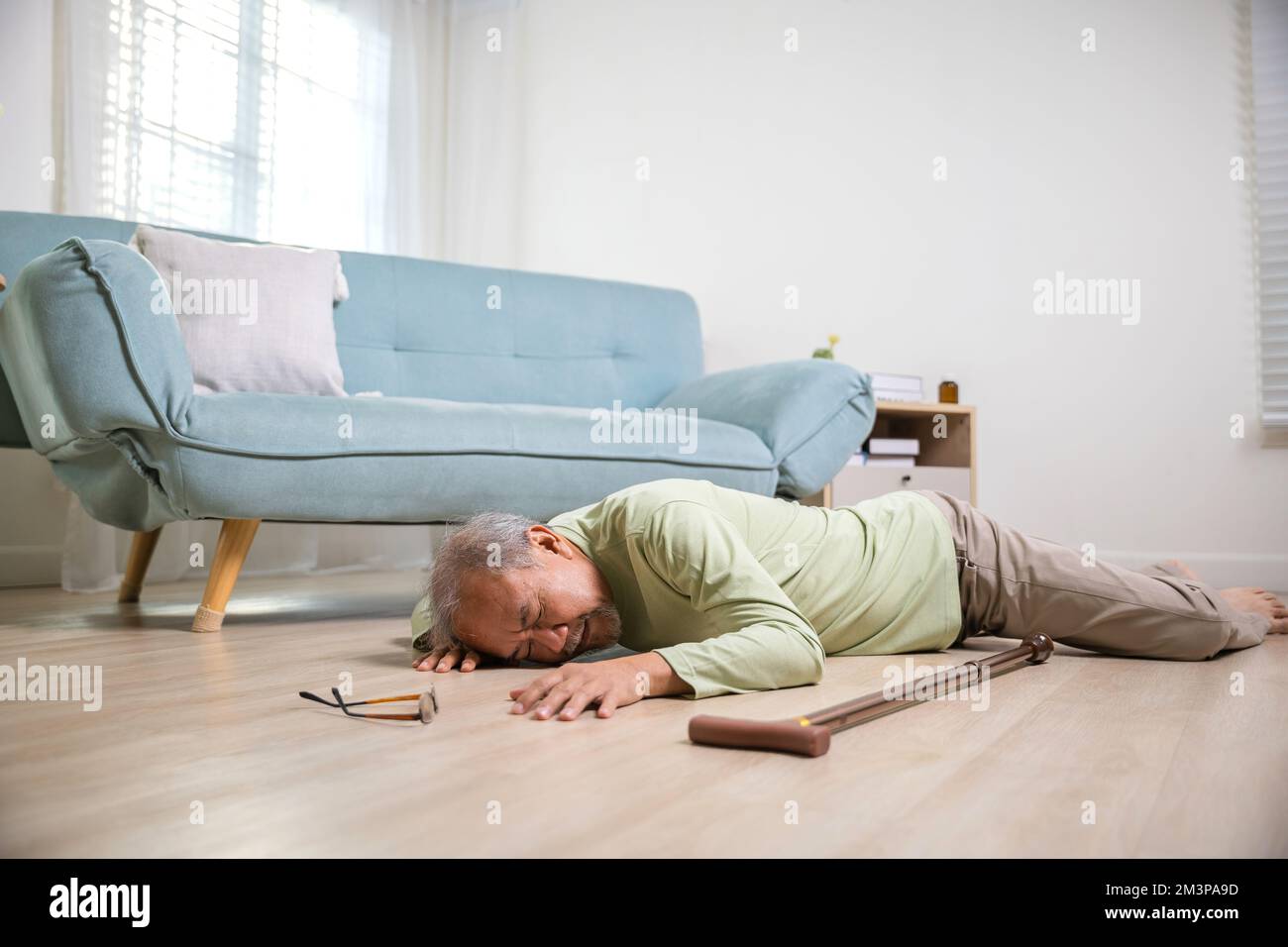 Elder man falling on the floor alone with walking stick on living room ...