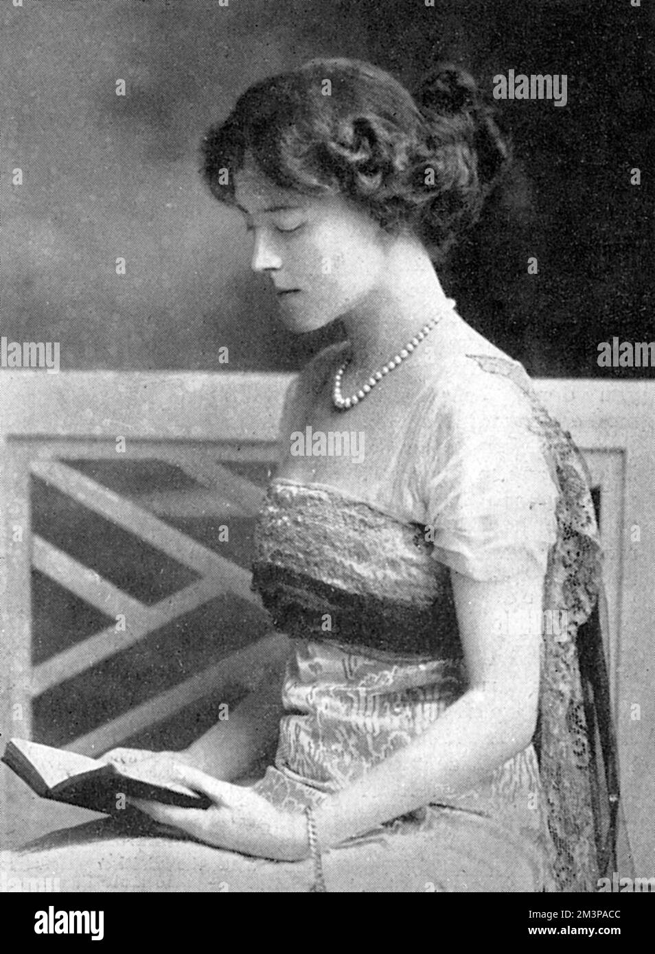 The Marchioness of Downshire, nee Evelyn Grace Mary Foster, pictured peacefully reading a book. At the time this picture was published, the Marchioness was lying dangerously ill with typhoid fever at Easthampstead Park, the 6th Marquis' Berkshire seat. She did not succumb to the fever however, and lived until 1942.     Date: 1915 Stock Photo