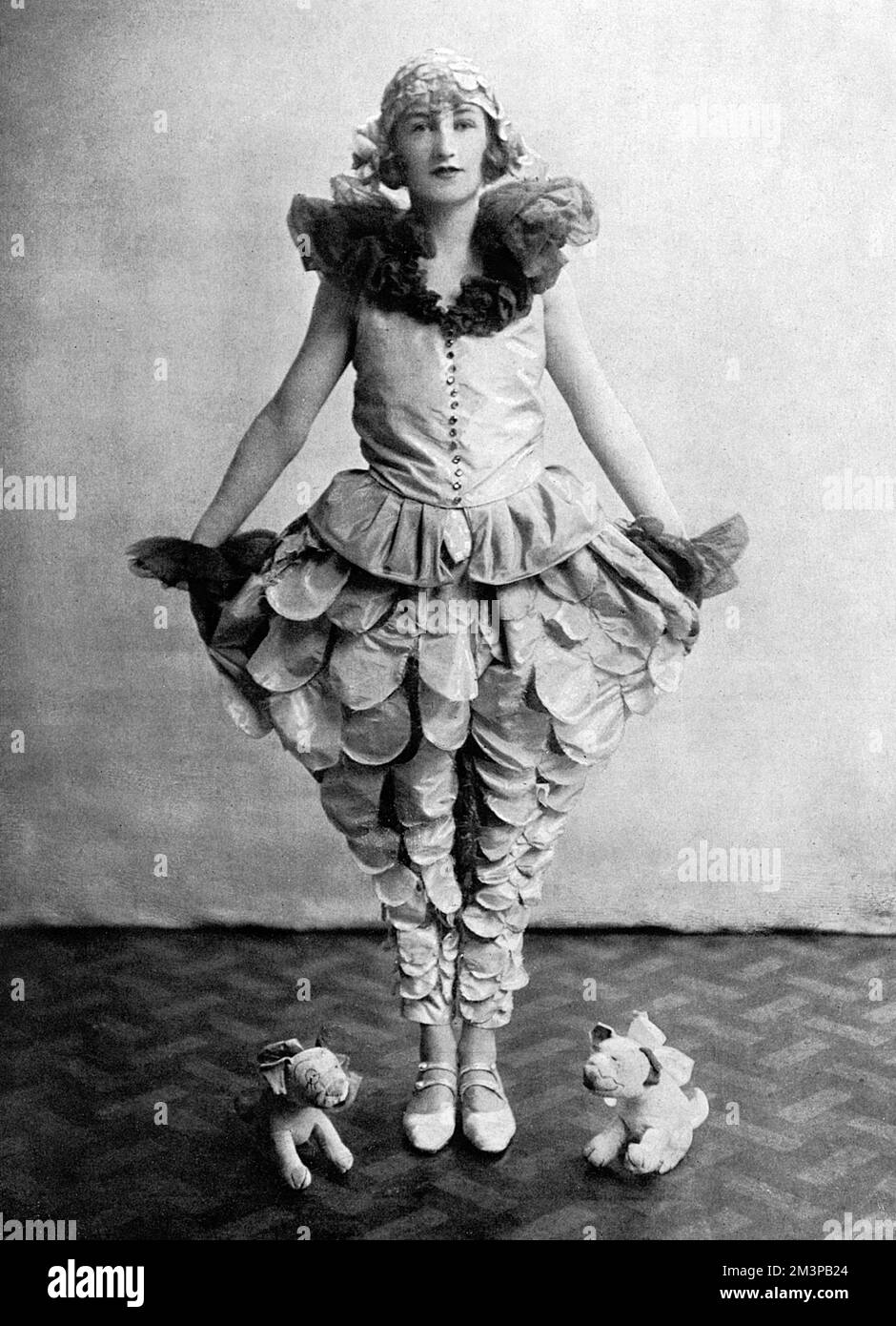 Actress Stephanie Stephens posed in one of her costumes from the musical comedy, Queen High at the Queen's Theatre in 1926.  At her feet are two plush toys in the image of the famous cartoon dog by George Studdy, Bonzo, who was at the height of his fame at that point.  The photograph is published in The Sketch - the magazine also published Studdy's cartoons of Bonzo.     Date: 1926 Stock Photo