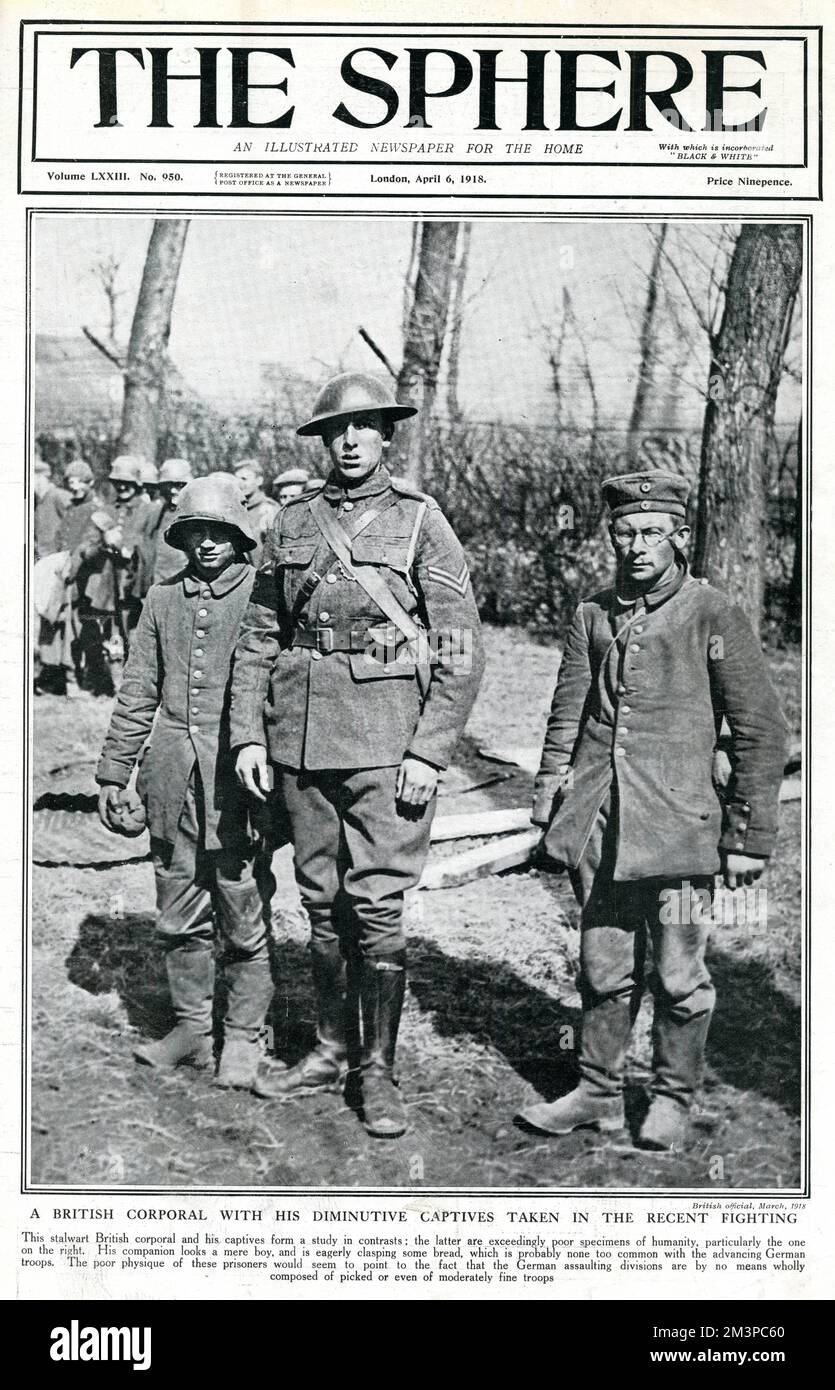 A stalwart British corporal pictured with two German captives in a photograph which deliberately highlights the difference in stature of the men.  The Sphere calls them, 'exceedingly poor specimens of humanity.'  The young soldier on the left of the picture is holding some bread which, 'is probably none too common among the advancing Germans.'     Date: 1918 Stock Photo