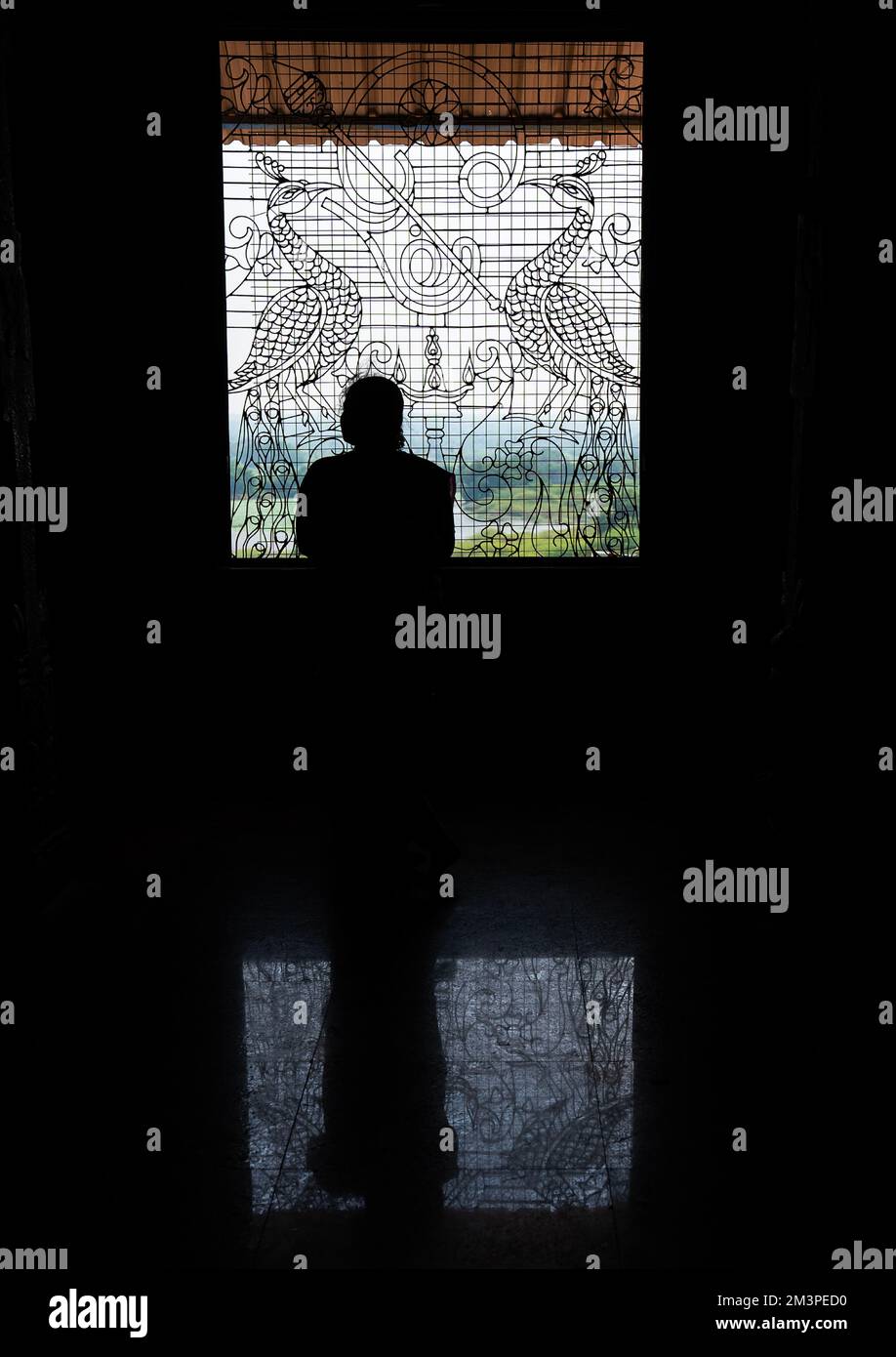 People silhouettes in front of artistic iron work window, Tamil Nadu, Chettinad, India Stock Photo