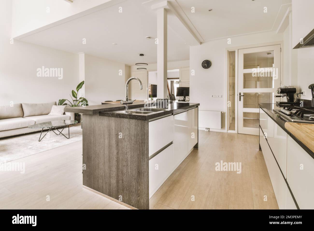a kitchen and living room in a modern apartment with white walls, wood