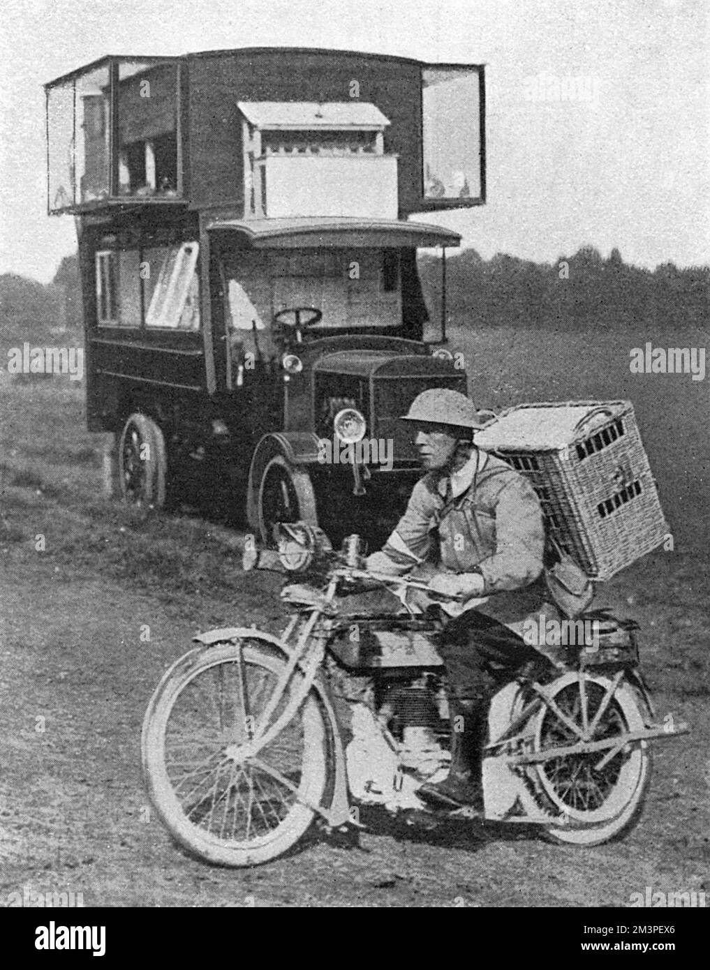 H.M. &quot;Air&quot; Service - Petrol and Pigeons at the Front.  A motor lorry behind the lines, converted into a home for carrier pigeons, used to carry message at the front.  A despatch rider is seen in the foreground, starting out with a basketful of birds for service in the trenches.     1917 Stock Photo