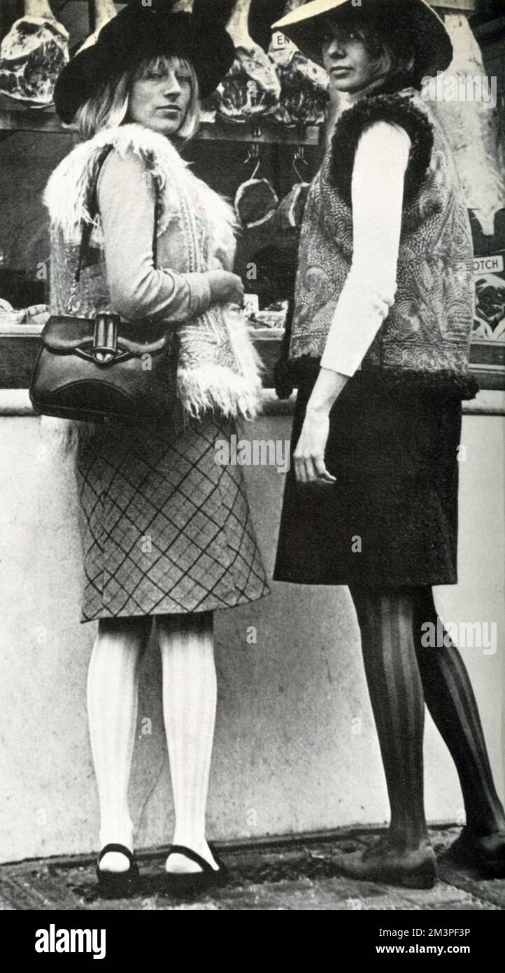 Emma Booker and Clare Peploe, standing in front of a butcher, both wearing yellow embroidered Afghan sheepskin jackets, which are prototypes of ones they will sell in their shop The Yellow Room.     Date: 1966 Stock Photo