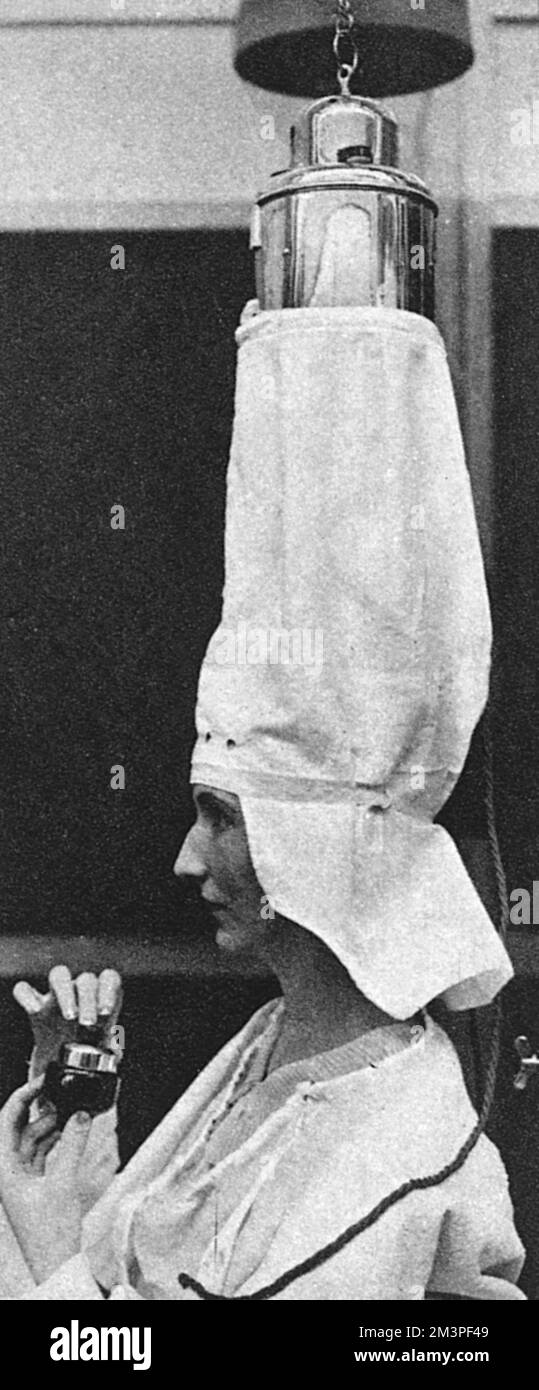 An electrically heated drying bag for hair, as seen at the Hairdressers' Annual Exhibition at the White City, London, 1928     Date: 1928 Stock Photo