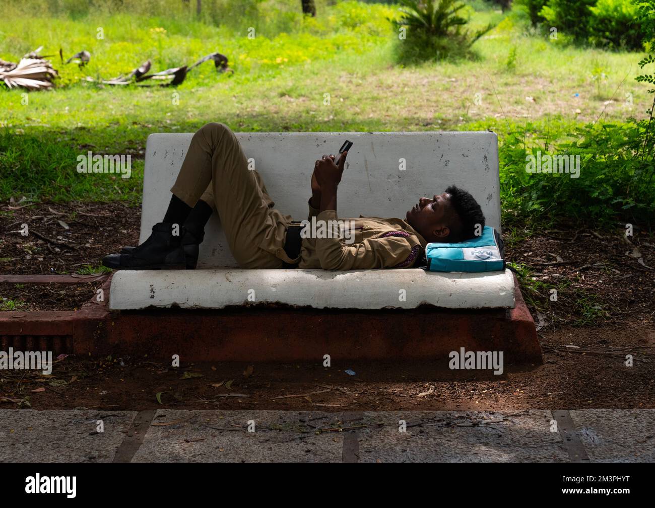 Indian soldier texting on his mobile phone on a bench in a park, Pondicherry, Puducherry, India Stock Photo