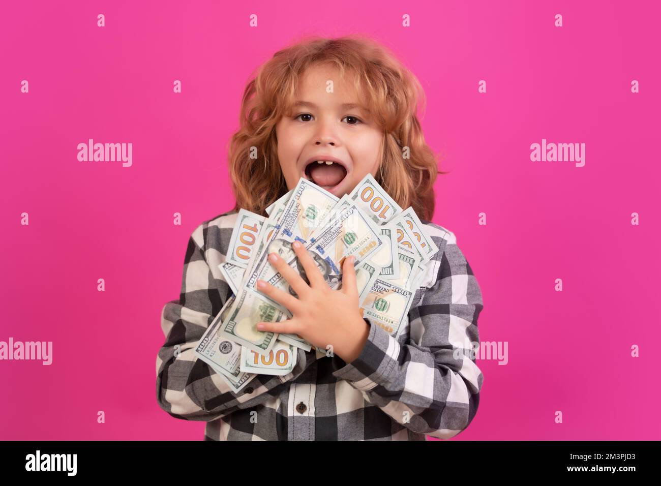 Child with lots of money dollar banknotes isolated over pink red studio background. Stock Photo