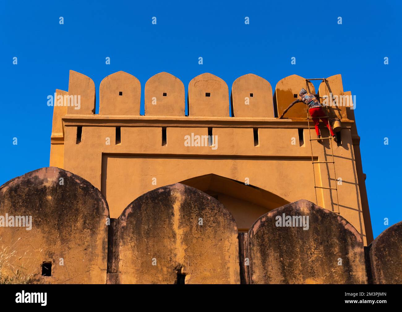 Indian man painting Amber Fort rampart, Rajasthan, Amer, India Stock Photo