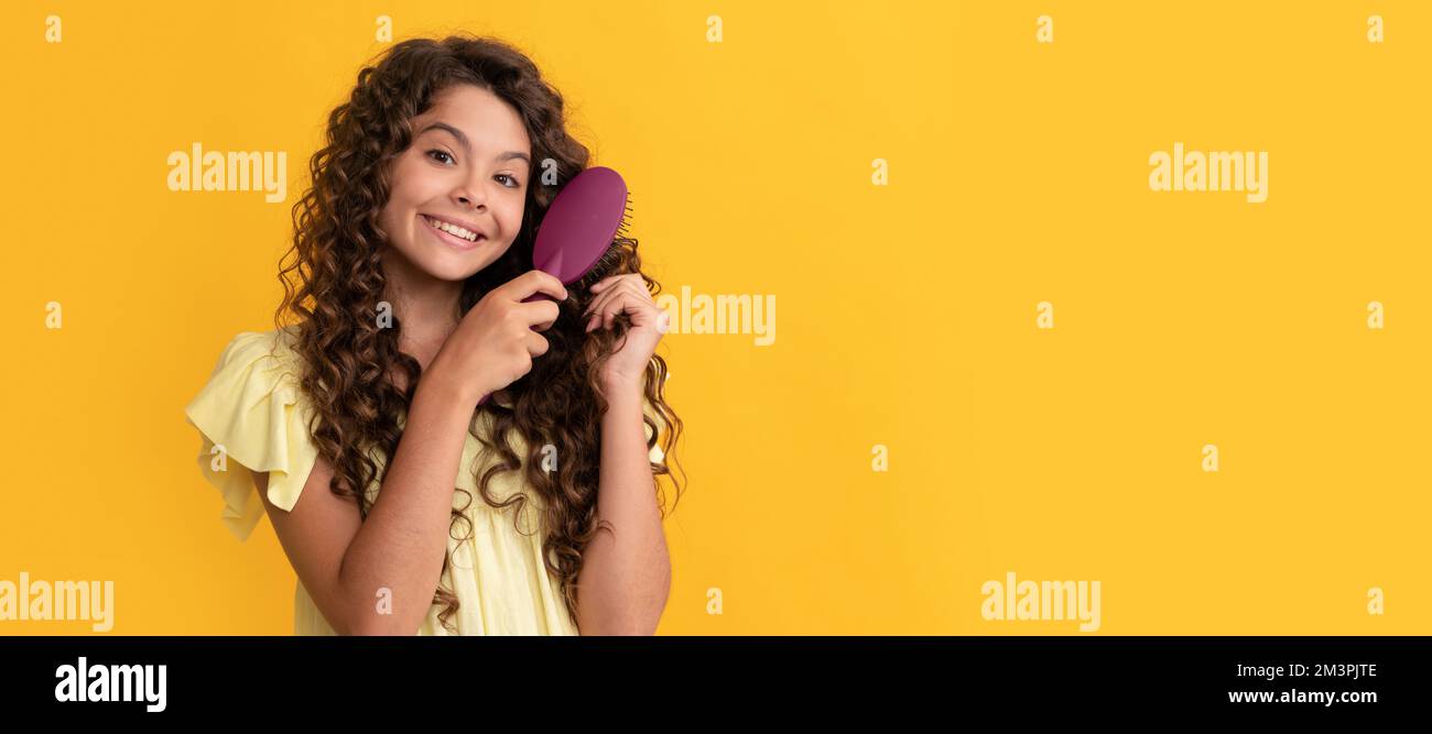 hairdresser. kid smile with curly hair hold hairbrush. teen beauty hairstyle. Kid girl hair care, horizontal poster. Banner header with copy space. Stock Photo