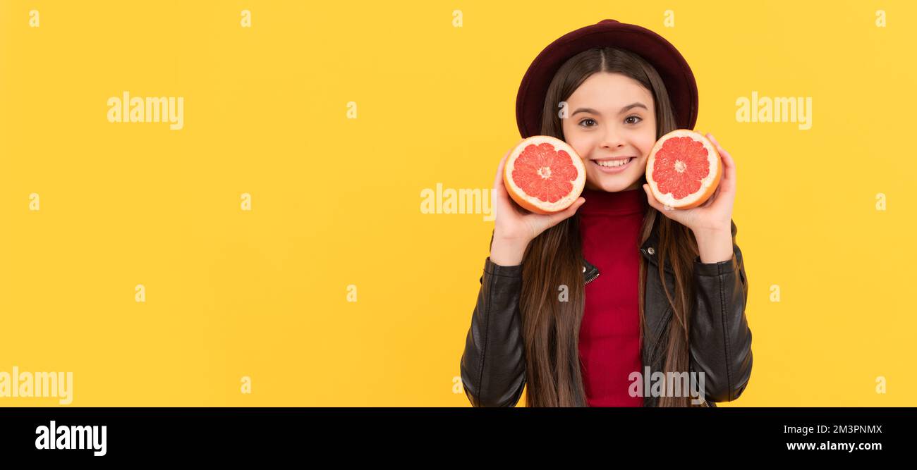 happy teen girl in hat and leather jacket hold cut grapefruit. Child girl portrait with grapefruit orange, horizontal poster. Banner header with copy Stock Photo