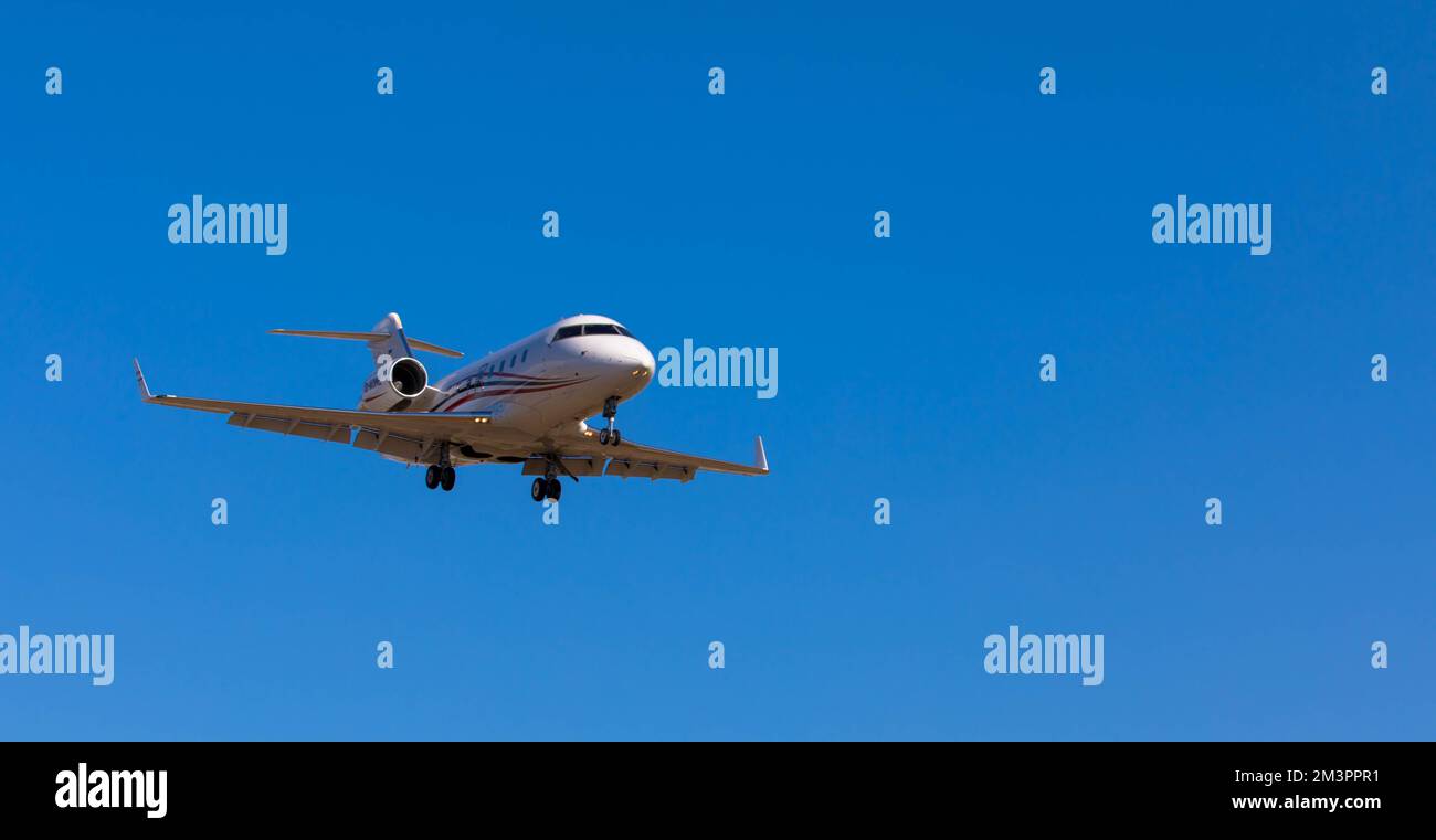 Private jet on approach for landing. Blue sky with plenty of space for text. Stock Photo