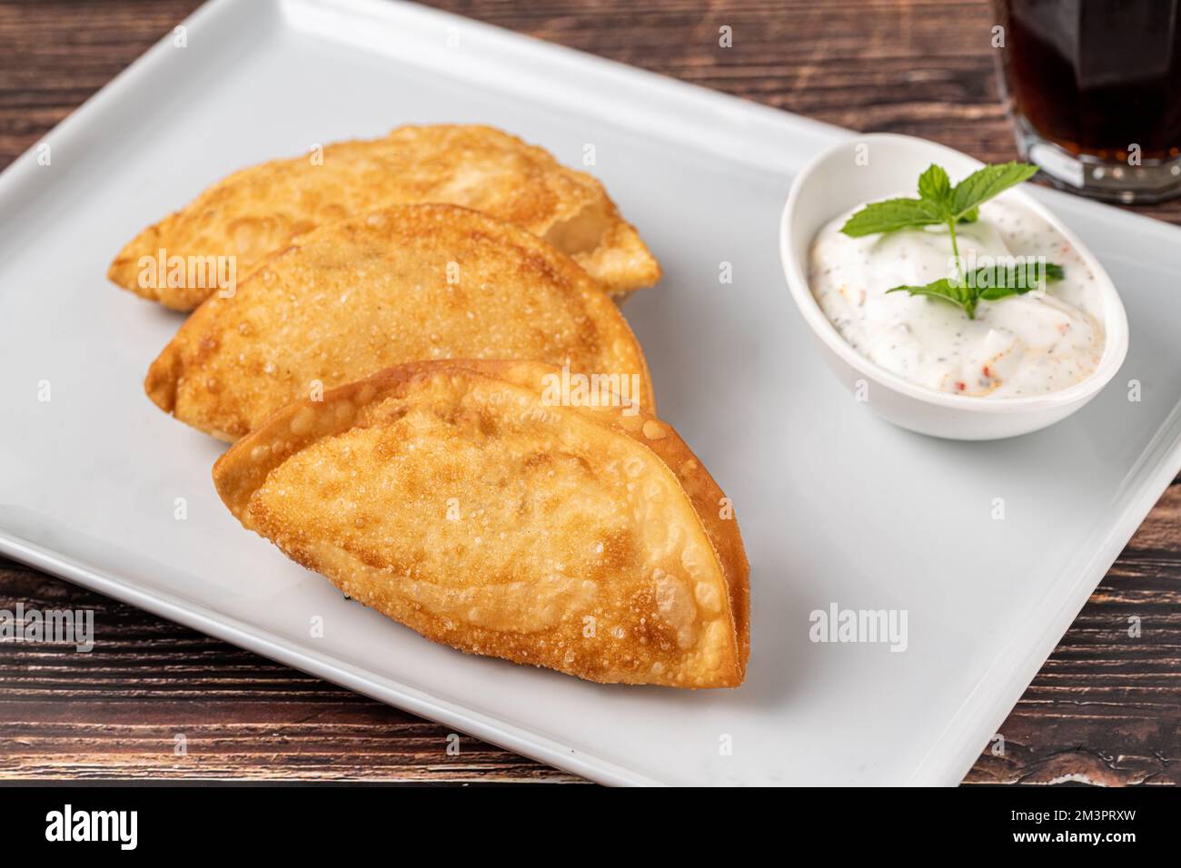 Beef Cheburek on a wooden table. Deep Fried Beef Dumplings with meat and onions. Turkish name Ci Borek or Cig Borek Stock Photo