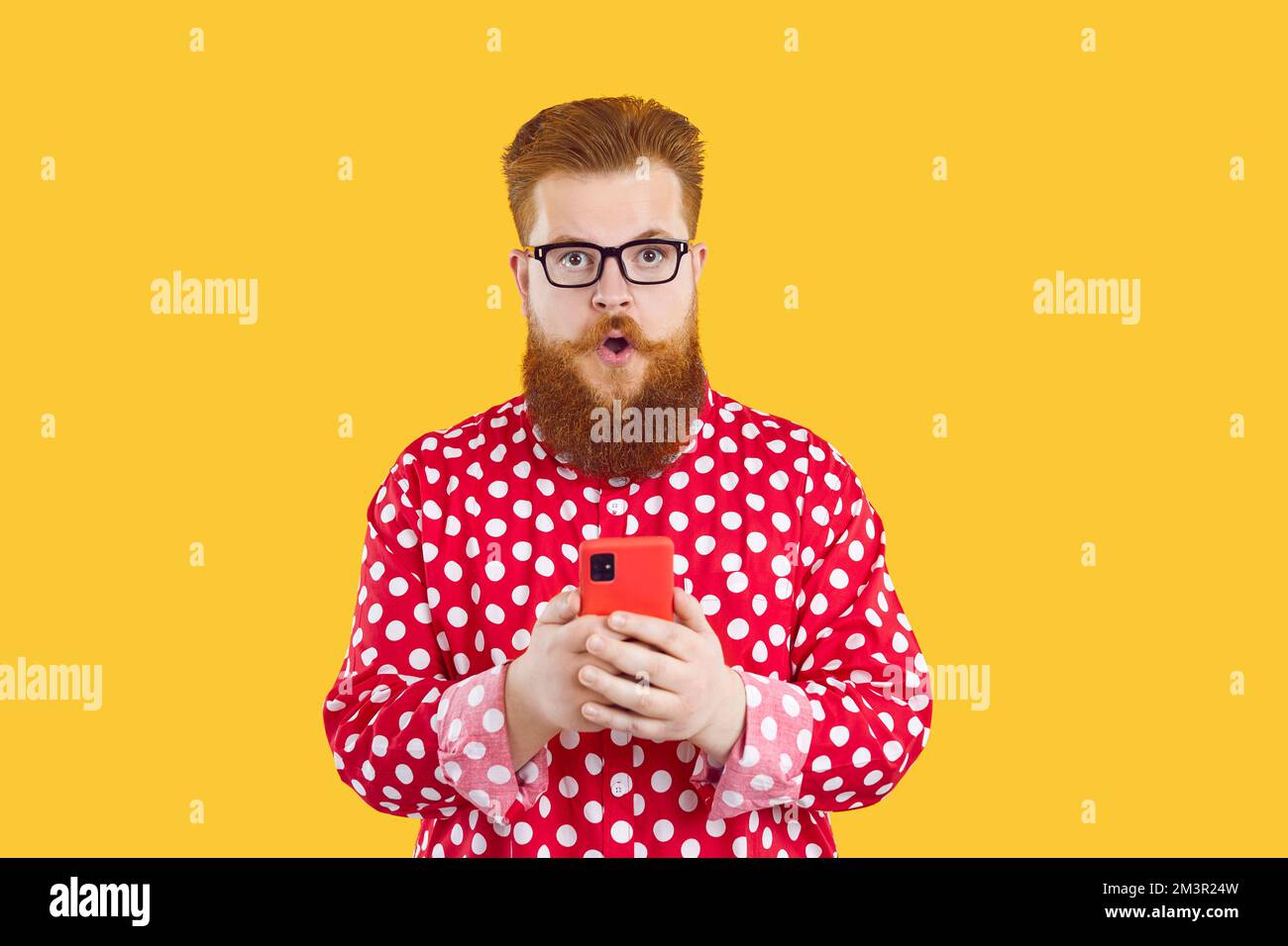 Funny fat bearded guy in glasses gets surprised by notification on his mobile phone Stock Photo