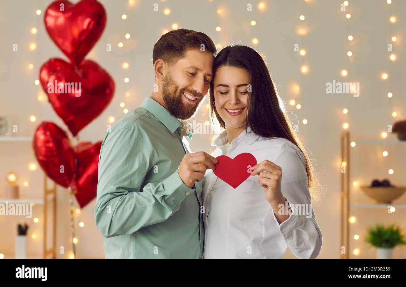 Portrait of happy young loving couple holding heart shaped card on ...