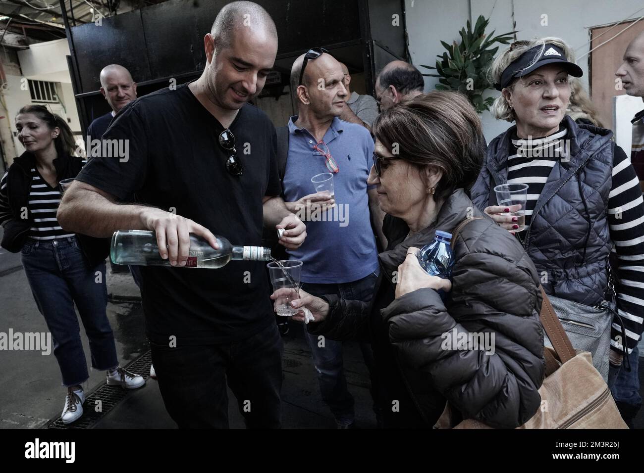 Tel Aviv, Israel. 16th December, 2022. A culinary tour guide pours wine for a tour participant at the Shuk HaCarmel Market, an outdoor marketplace est Stock Photo