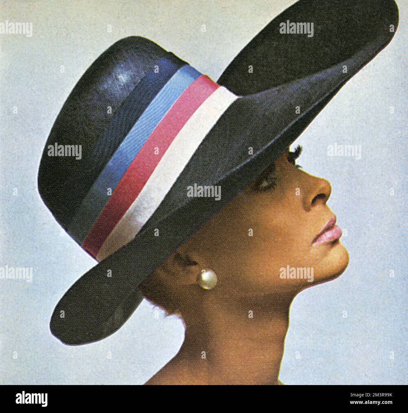 Model wearing a navy straw stetson with blue, pink and white band by Peter Shepherd. Worn with make-up by Max Factor.     Date: 1966 Stock Photo