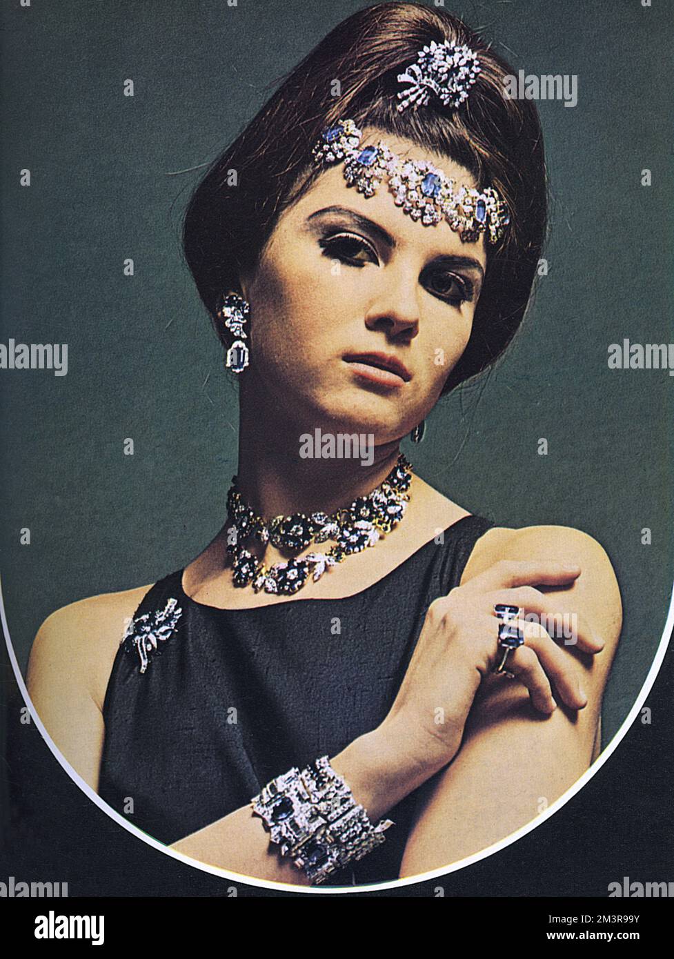 Model wearing sapphire, diamond and gold, sapphire and diamond bracelet, sapphire and diamond earrings, sapphire and diamond brooch and two sapphire single-stone rings from Mappin and Webb. This photograph is part of a special section of London Life presenting one million pounds' worth of jewelleries provided by ten of London's top jewellers of the 1960s.   1966 Stock Photo