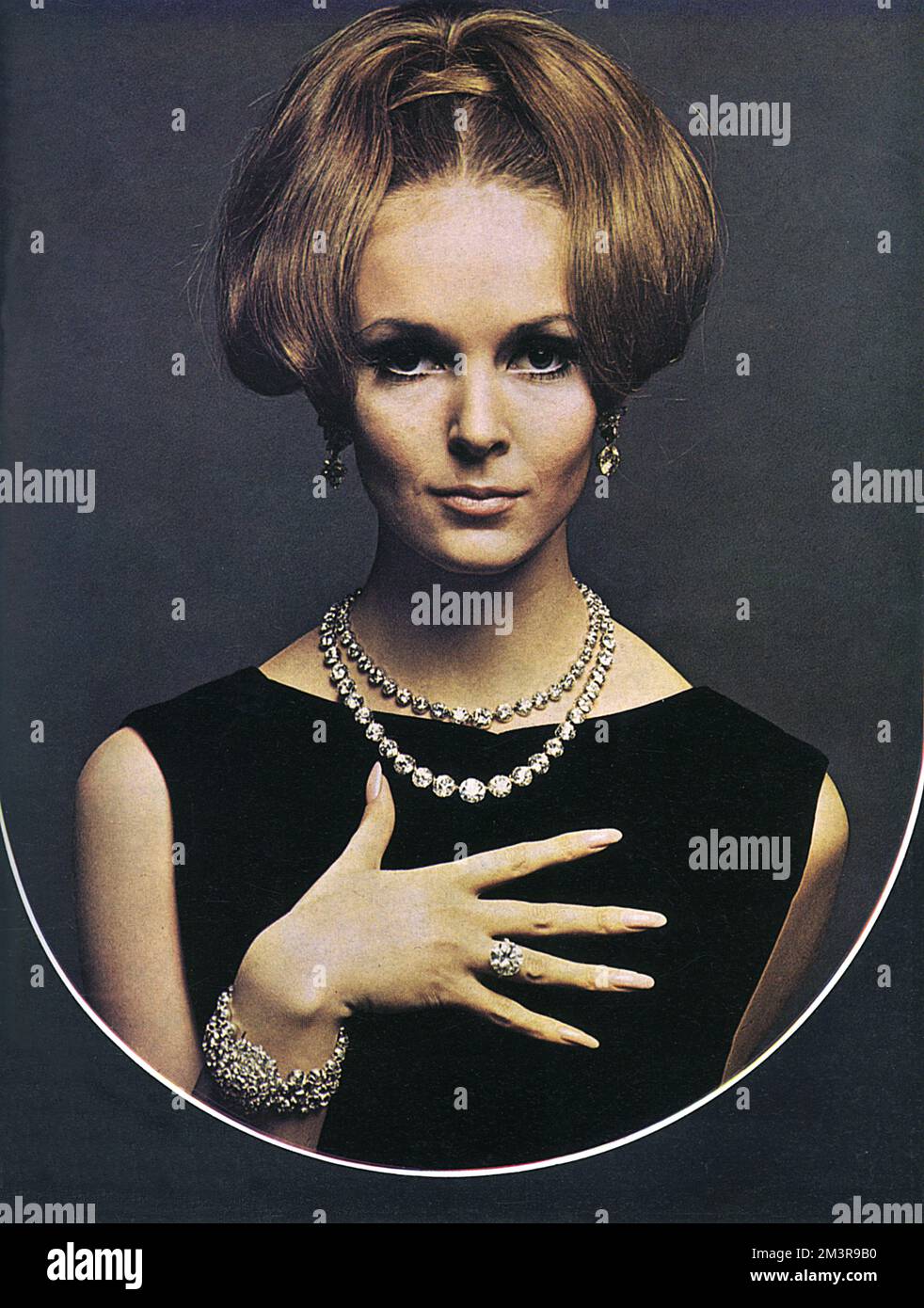 Model wearing a large and a small diamond collet necklace, a large diamond single-stone ring, navette and baguette earrings with diamond collet drops, a three-row collet bracelet with a diamond cluster centre from Collingwood of Conduit St. This photograph is part of a special section of London Life presenting one million pounds' worth of jewelleries provided by ten of London's top jewellers of the 1960s.      Date: 1966 Stock Photo