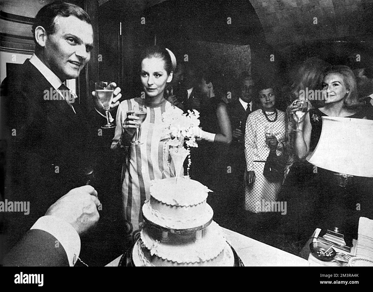 Wedding reception after the marriage of publicist and London Life contributor David Wynne-Morgan and Sandra Paul, model, held at Annabel's club in Berkeley Square.  The wedding party can be seen gathered around the happy couple and the wedding cake raising a toast.  Wynne-Morgan was Sandra's second husband.  She is now married to politician Michael Howard and is a writer.       Date: 1966 Stock Photo