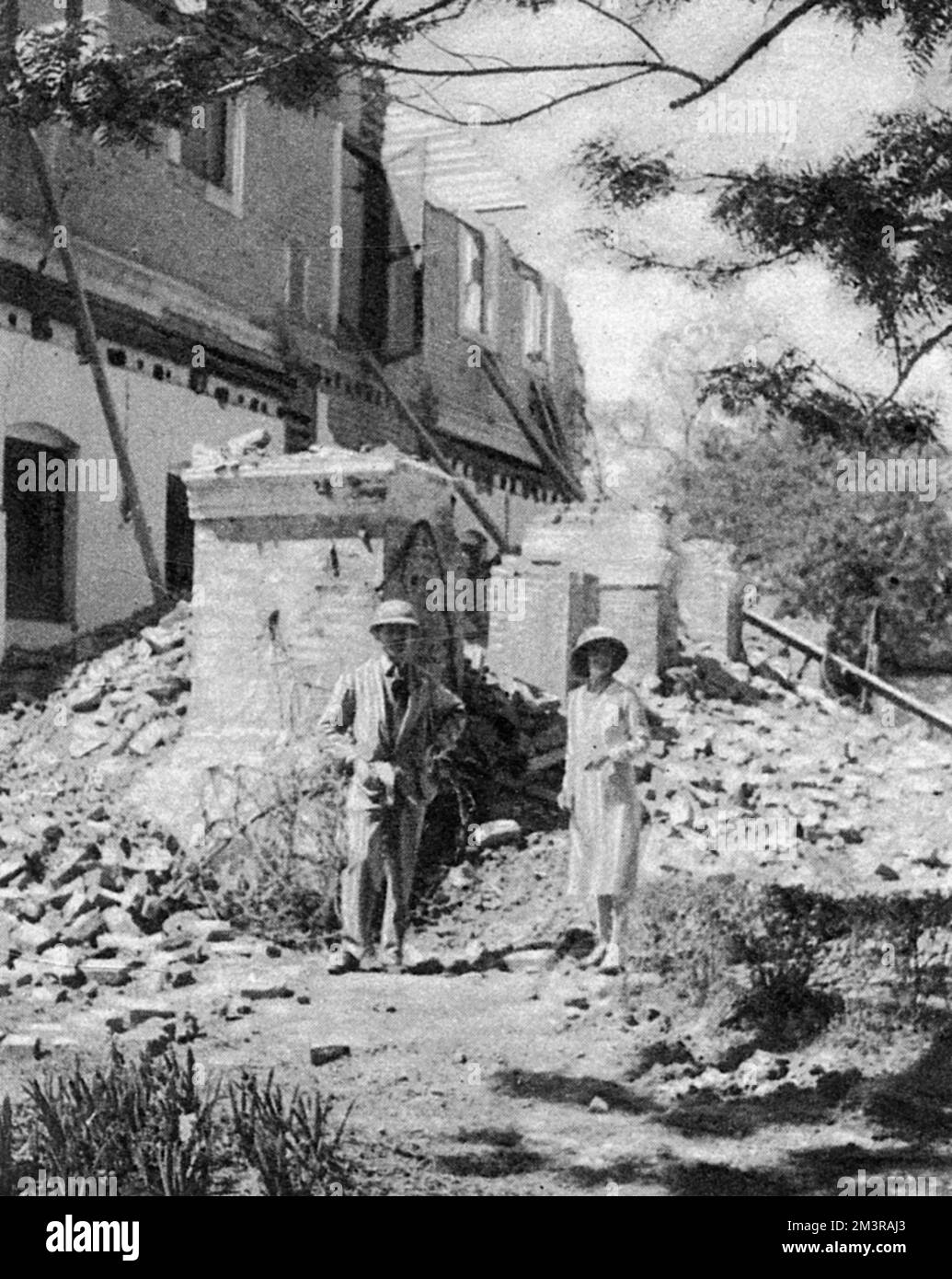 Mr. and Mrs. Kilburn outside the ruins of their bungalow at Katmandu: the state engineer of Nepal, and one of the few Europeans in the country, all of whom escaped injury.       Date: January 1934 Stock Photo