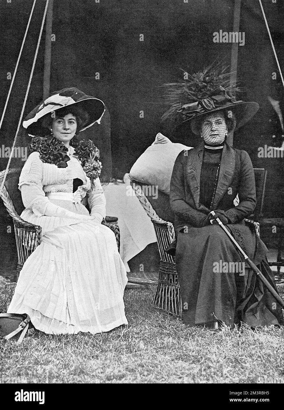 Queen Ena of Spain (1887-1969), formerly Princess Victoria Eugenie of Battenberg, granddaughter of Queen Victoria, pictured at Eaton Hall in Cheshire with her hostess, Shelagh, Duchess of Westminster during a polo match played on the duke's private ground in the park adjacent to the house.  The Tatler comments that, 'The Duke and Duchess of Westminster always entertain on a princely scale and are admirable hosts.'     Date: 1910 Stock Photo