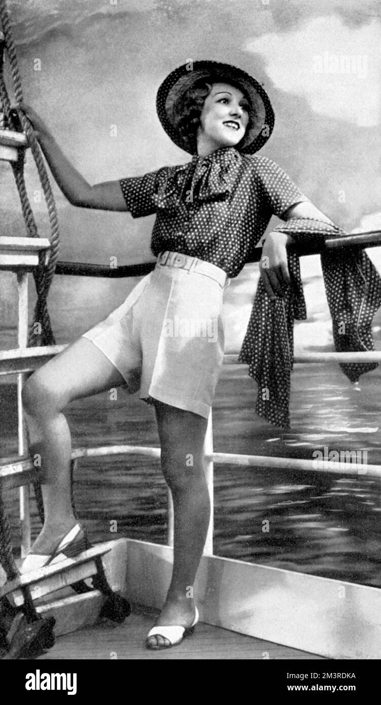 Smart, tailored shorts outfit from Harvey Nichols, suitable for beach and deck wear comprising of shorts in an off white shade, whilst the jacket and coat are of polka dot navy.  The entire sheme is carried out in shantung silk.  1934 Stock Photo