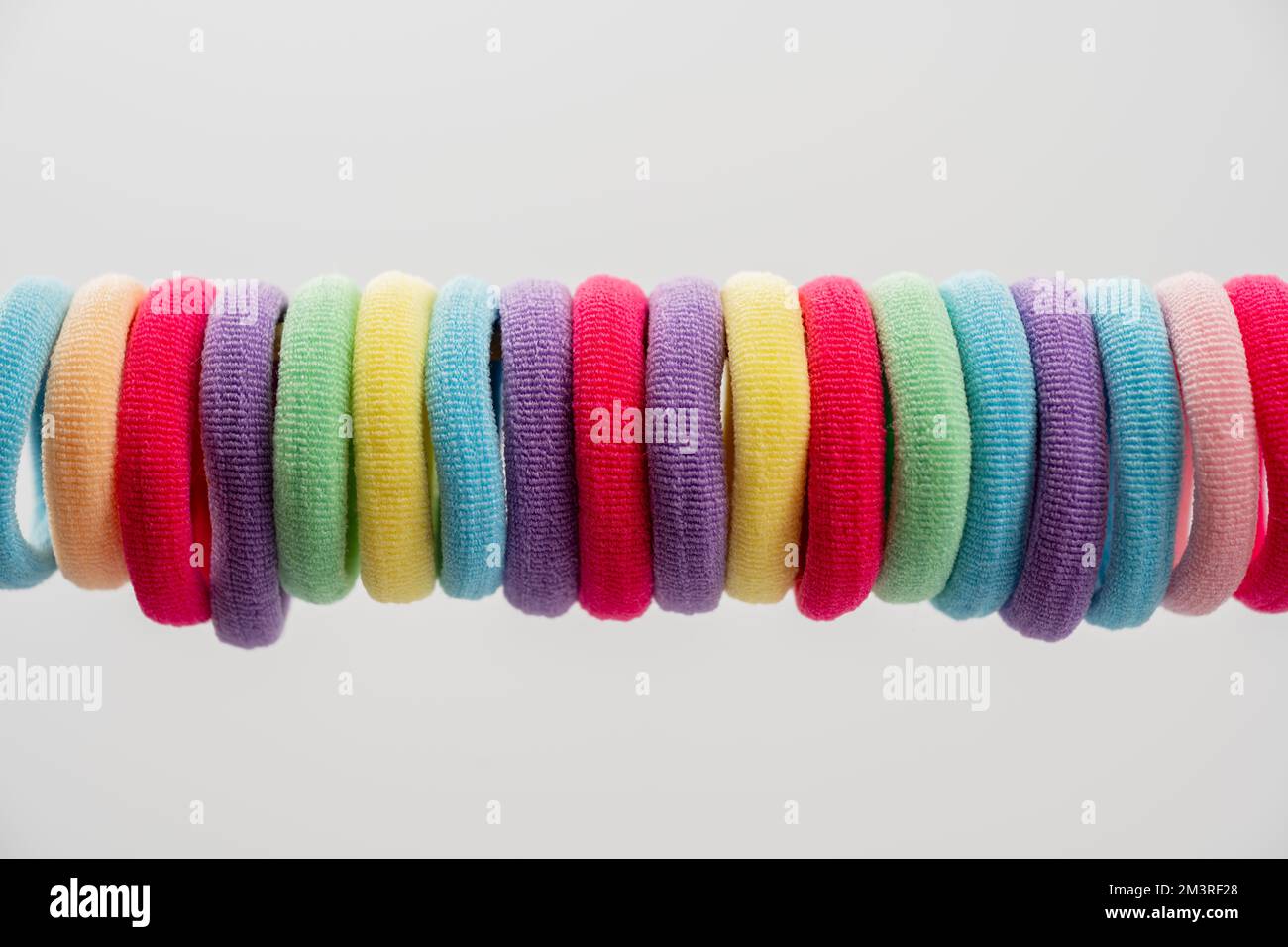 string of brightly colored elastic round hair bands isolated on a white background Stock Photo