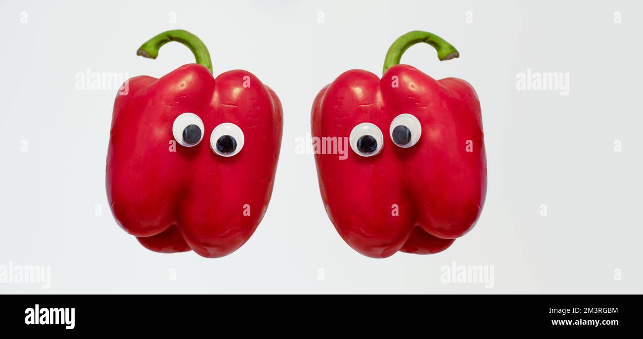 Two red Bell Peppers with googly eyes isolated on a white background