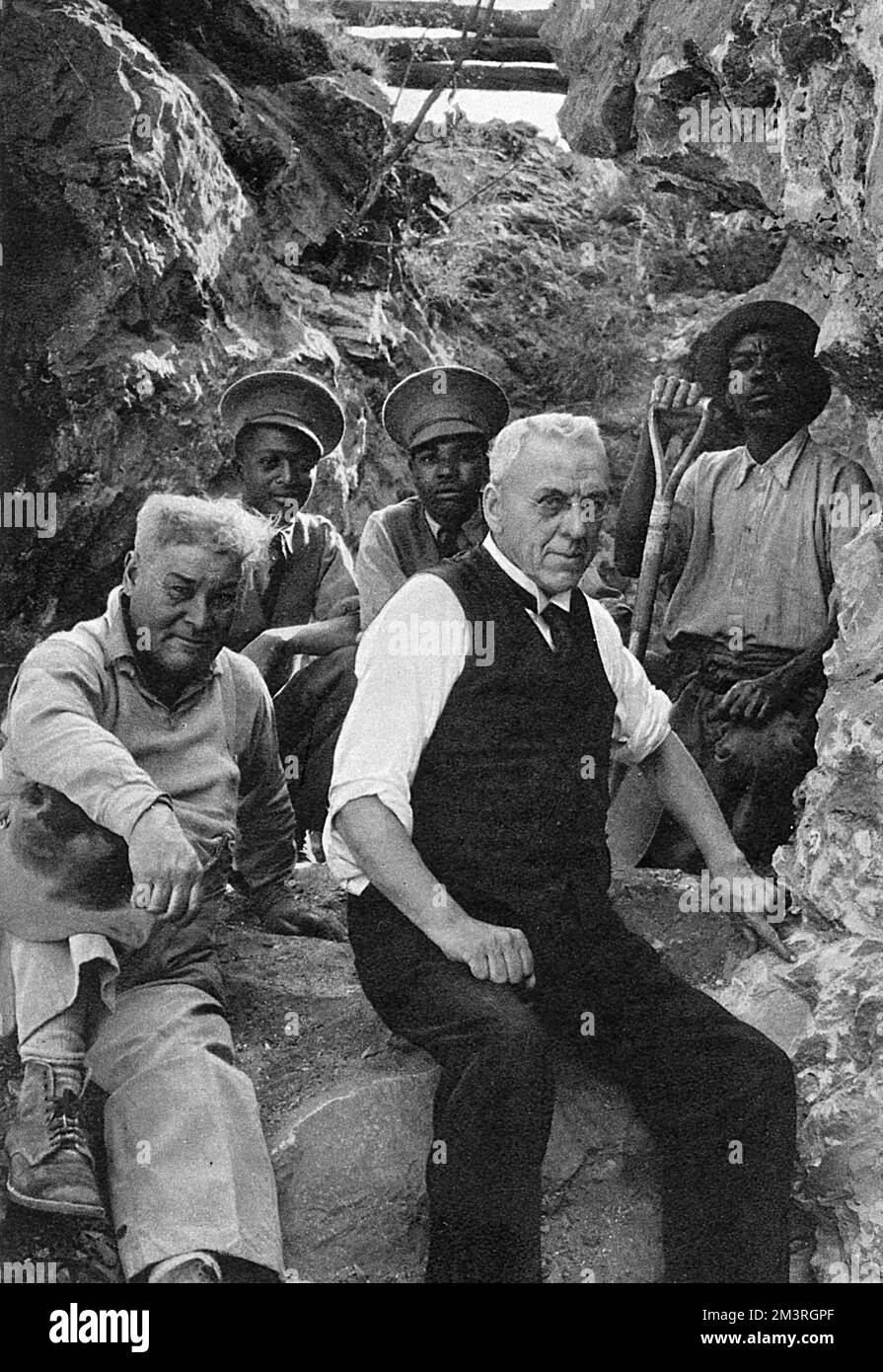 An important discovery in South Africa: the brain-cast and parts of the skull of an anthropoid ape with human characteristics. Dr. Robert Broom paleontologist of the Transvaal Museum, Pretoria, is pictured with his hand on the exact spot where the skull lay, and (on the left) Mr. W. G Barlow, manager of the lime works at Sterkfontein, near Krugersdorp, who had given him the brain-cast blasted out two days before.     Date: 1936 Stock Photo