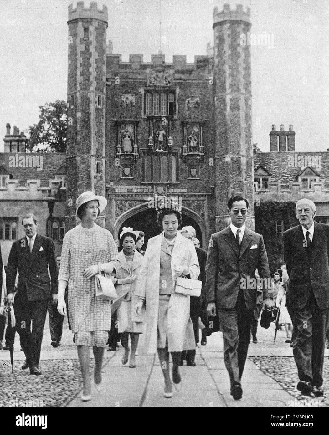 An official two-day state visit to the UK by King Bhumibol Adulyadej (Rama IX) (1927-) and Queen Sirikit (1932-) of Thailand - visiting Cambridge (walking through the Great Court of Trinity College) accompanied by Princess Alexandra of Kent (1936-) and Lord Adrian (Edgar Douglas Adrian, 1st Baron Adrian OM PRS - an English electrophysiologist and recipient of the 1932 Nobel Prize for Physiology, won jointly with Sir Charles Sherrington for work on the function of neurons) (1889-1977).     Date: 1960 Stock Photo