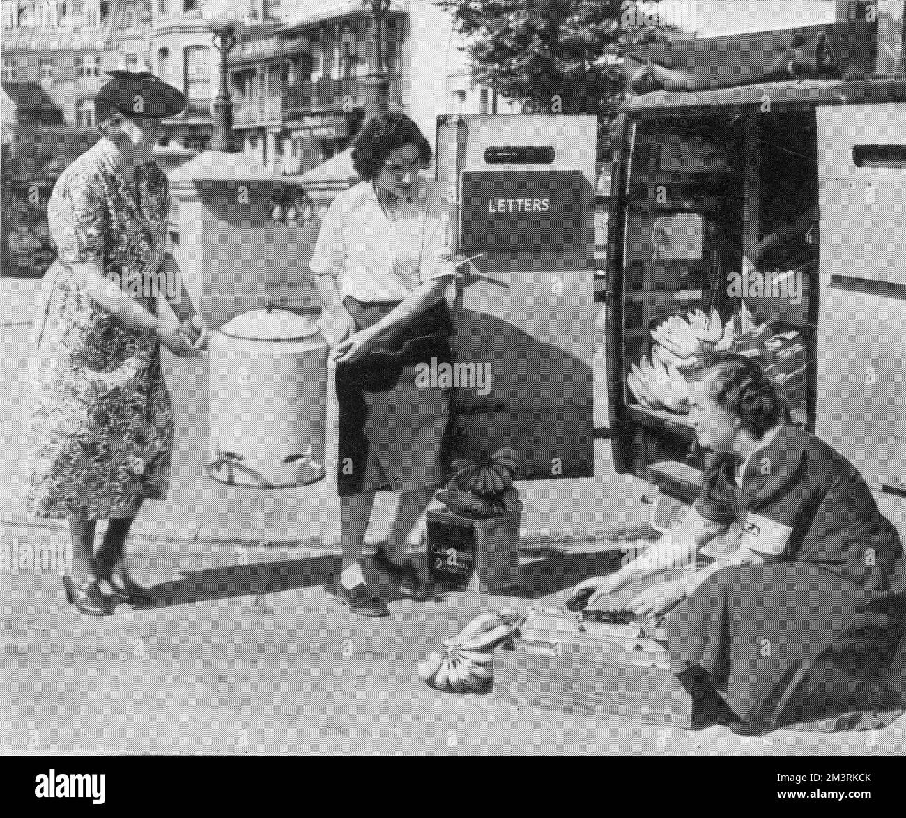 Women loading an urn onto a mobile canteen in Brighton. Bananas and cakes can also be seen.  1940 Stock Photo