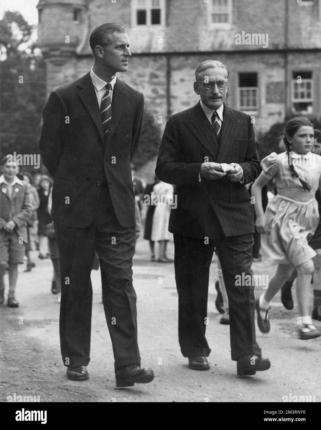 Prince Philip, Duke of Edinburgh visiting a fete at his old school, Gordonstoun in 1949, his first official visit.  Pictured wearing the old school tie of purple and white and walking with Colonel Shaw-Zambra.     Date: 1949 Stock Photo