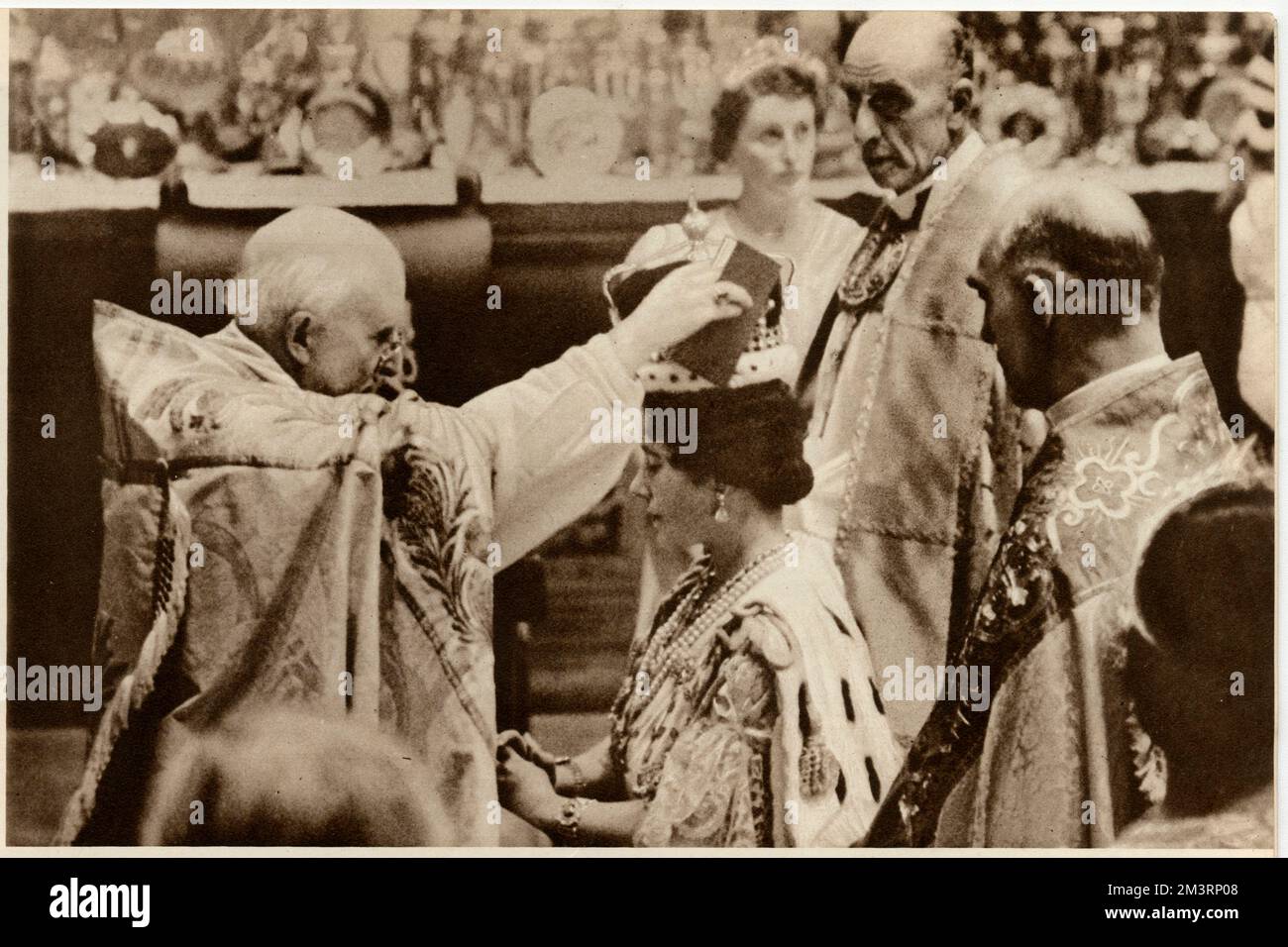 The Queen's Coronation. Her Majesty is kneeling on her faldstool and the Archbishop of Canterbury is placing the Crown upon her head, with the koh-i-noor diamond glittering. Her Majesty is flanked by her two attendant Bishops, the Bishop of Blackburn and St. Albans.     Date: 12 May 1937 Stock Photo
