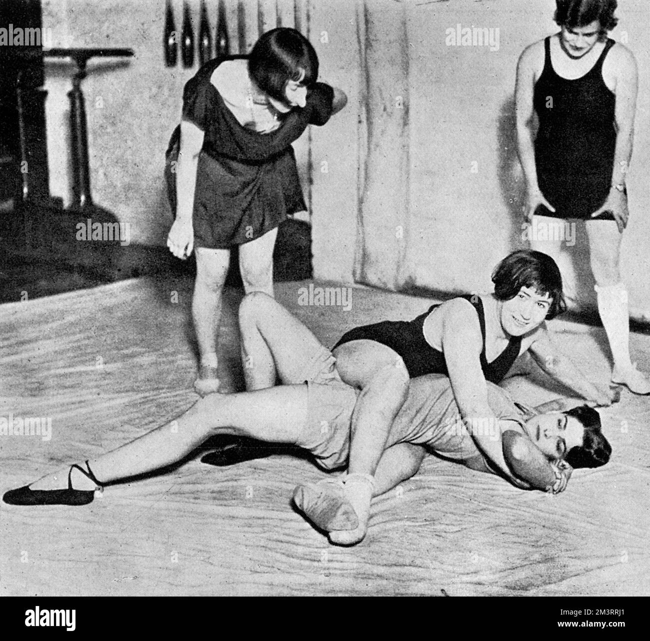 Gladiators of the feminine age.  A wrestling school for women recently opened in Vauxhall, London.  Miss Dot Butler, the school's champion wrestler, who recently issued an open challenge to any man of her own age (twenty-two) under ten stone, is showing one of her grips in a bout with Miss Bina Theodore, another assistant.       Date: 1928 Stock Photo