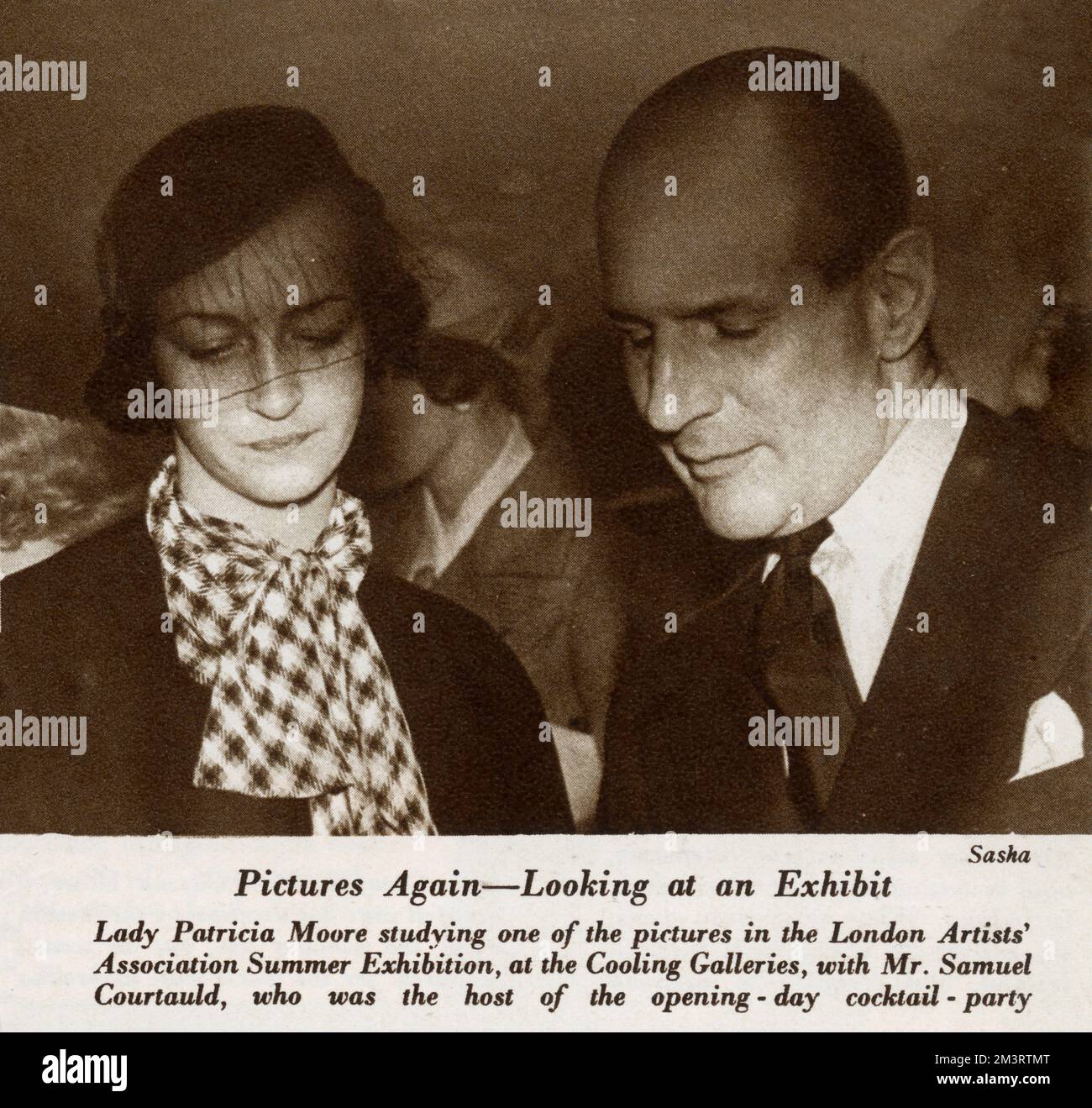 Lady Patricia Moore and Samuel Courtauld studying one of the pictures in the London Artists' Association Summer Exhibition at the Cooling Galleries.  Courtauld was the host of the opening day cocktail party.     Date: 1933 Stock Photo