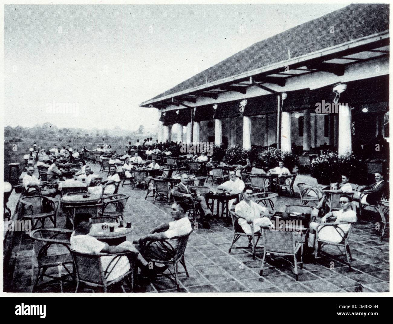 At the 19th! Members on the terrace of the Singapore Golf Club in 1936, the city's principal club with an active membership of 800. One of the outstanding and popular features is a battery of sixteen practise tees.     Date: 1936 Stock Photo