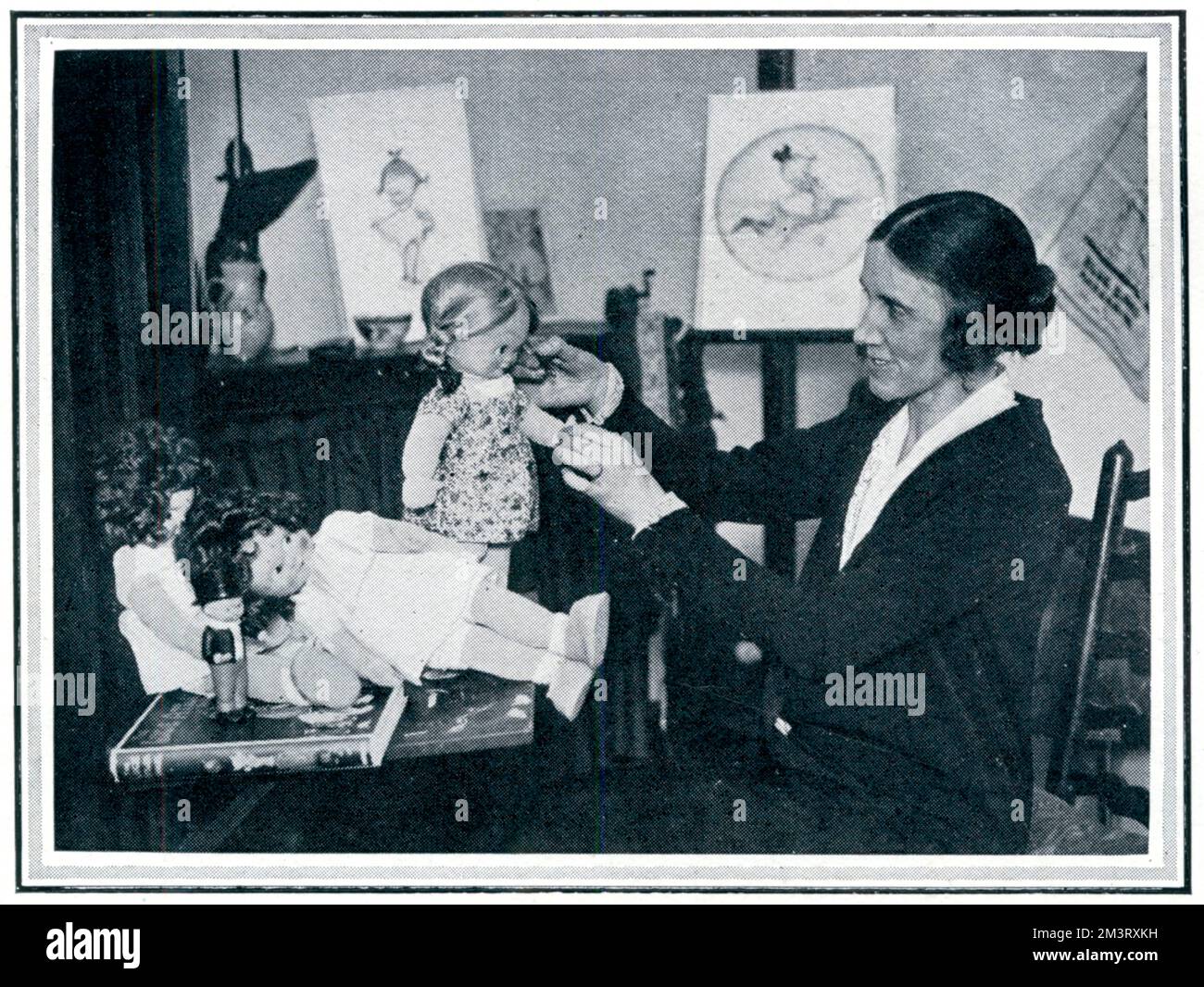 Mabel Lucie Attwell (1879 - 1964), artist best known for her pictures of  chubby cheeked children and fairies, pictured in her studio designing a group of dolls based on her famous drawings.       Date: 1924 Stock Photo