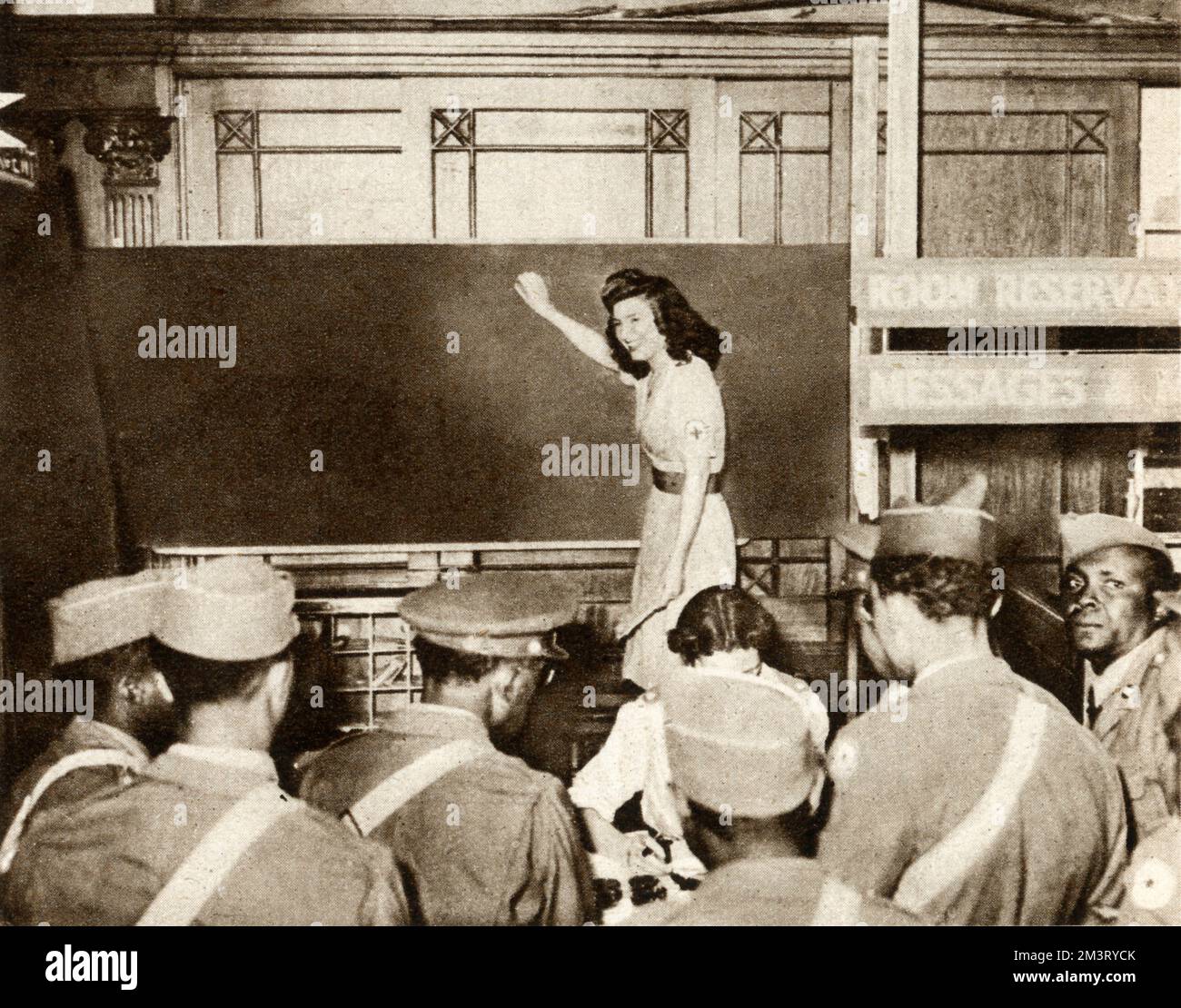 Black GIs in the Information Bureau at Rainbow Corner, the London American Red Cross Club. Thousands of messages are written on a large blackboard, calling soldiers on leave and soldiers to report to their units.     Date: 1944 Stock Photo