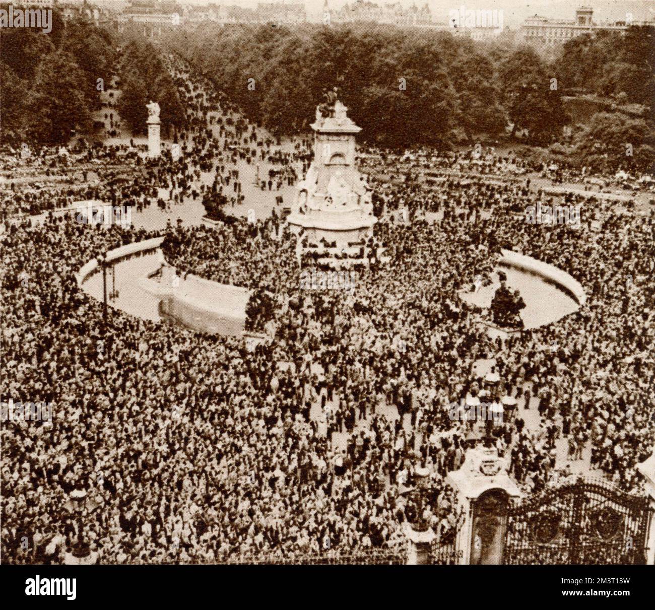People celebrating VE Day congregating in front of Buckingham Palace where eventually the royal family and Prime Minister will emerge to wave from the balcony. Stock Photo