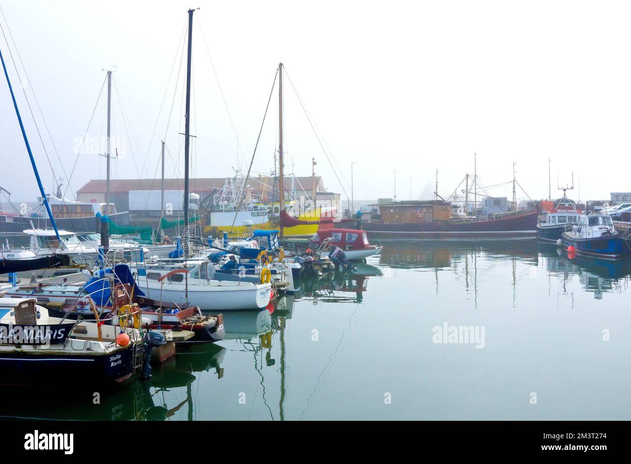 Fishing boats and pleasure craft docked in Arbroath harbour, Angus, Scotland, on a misty, foggy day. Stock Photo