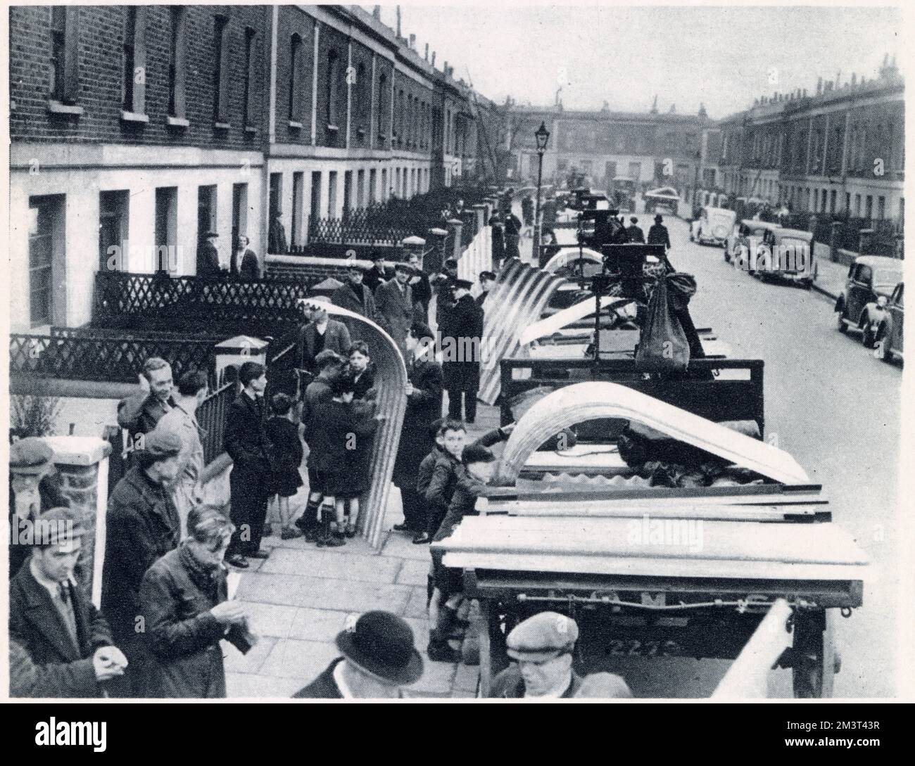 The first post-war delivery of the Government's steel for air-raid shelters in Tiber Street and Carlsbad Street, Islington, London. The sections were carried through the houses with much difficulty into the small backyards behind. The erecting of the shelters state that they had to be buried three feet in the ground and most of these where paved with concrete. Stock Photo