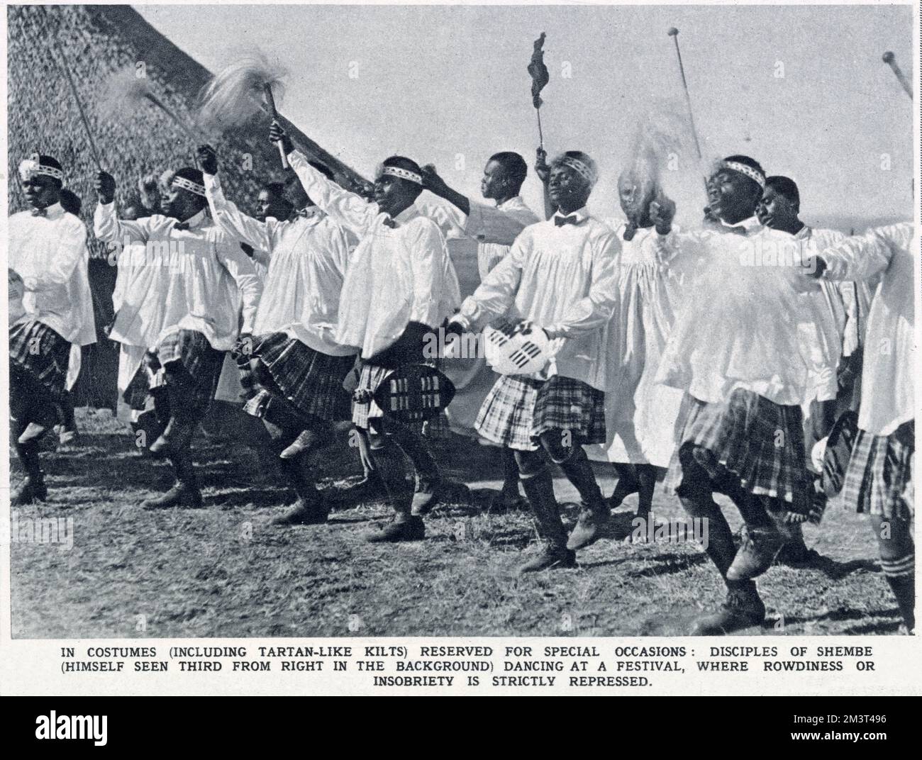 Disciples of Shembe (himself seen third from right in the background), dancing at a festival in costumes, including tartan-like kilts, reserved for special occasions. Rowdiness or insobriety is strictly repressed. Isaiah Shembe (c.1865-1935) was a native prophet and healer of Inanda, Natal, and the founder of the Ibandla lamaNazaretha (Church of Nazareth), South Africa, the largest African-initiated church in Africa during his lifetime. Stock Photo