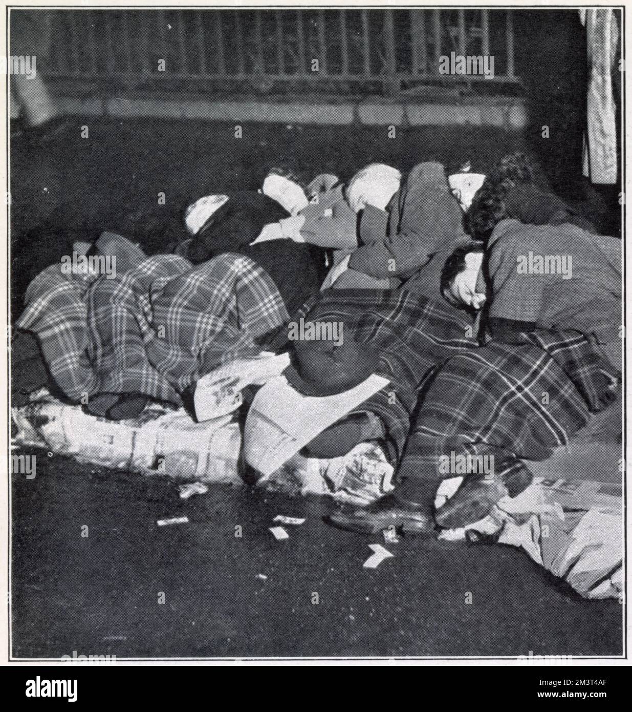 People who have staked their place along the route of King George V's funeral procession catching some sleep on the pavement on Piccadilly at 3am in the morning. Stock Photo