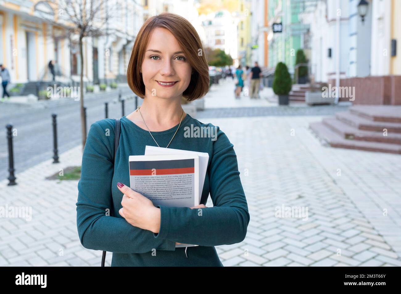 Cute happy girl student holds textbooks in her hands, and looks at the ...