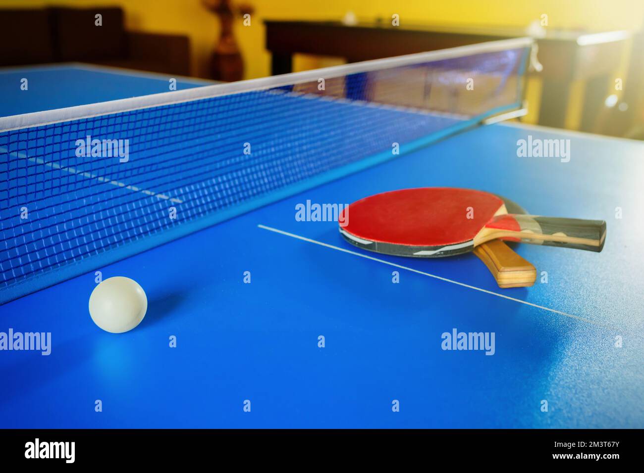Two rackets for a table tennis or PingPong and a ball on a blue table